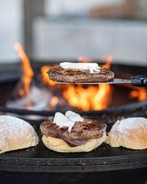 Burger Zubereitung, Wagyu Burger Patty angebraten mit Zwiebeln, Wagyu Burger Set kaufen, Burger Set mit Wagyu-Patties, Wagyu Burger aufgeklappt am Feuer